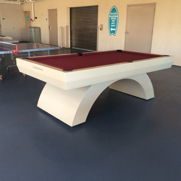 A pool table in the middle of an indoor court.