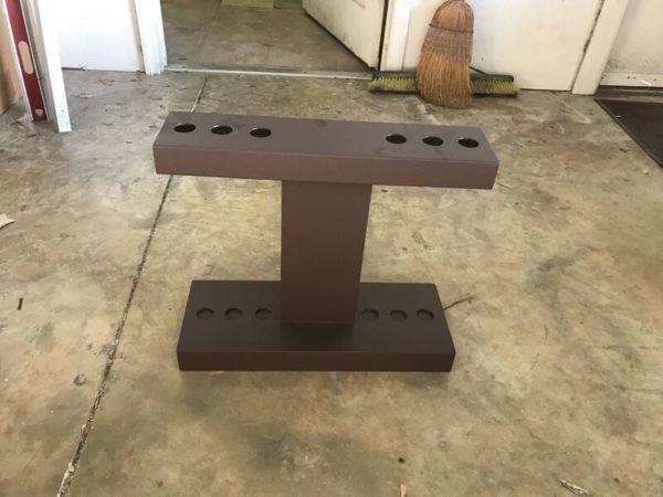 A metal stand with four holes for multiple pipes.