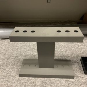 A gray stand with six holes on top of it.