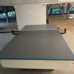 A table tennis table in the middle of an unfinished room.