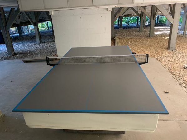 A table tennis table in the middle of an unfinished room.