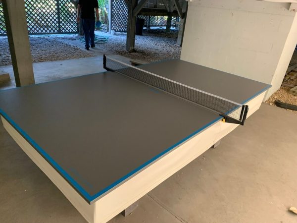 A table tennis table with two paddles and one ball.