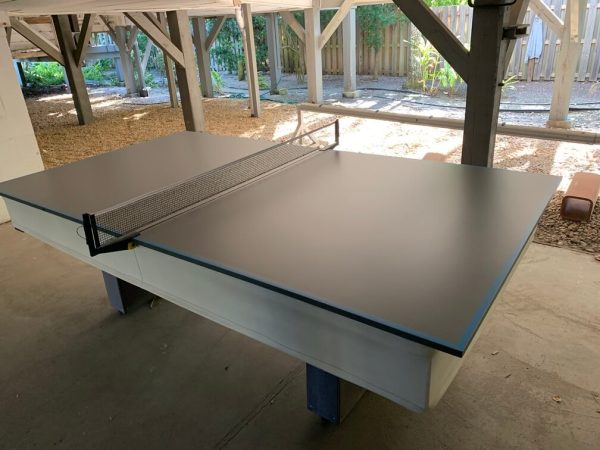 A table tennis table in the middle of an indoor court.